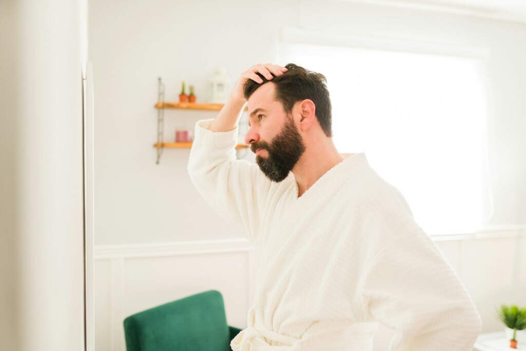uomo che si guarda allo specchio in bagno